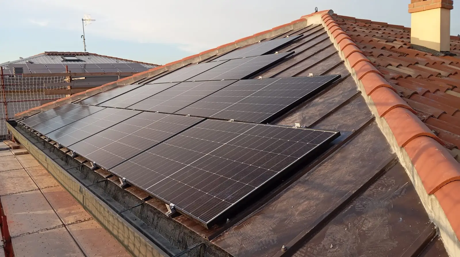 Impianto fotovoltaico installato sul tetto di Casa C.S.: pannelli solari neri su coperture in laterizio rosso, integrazione energetica sostenibile in ristrutturazione.