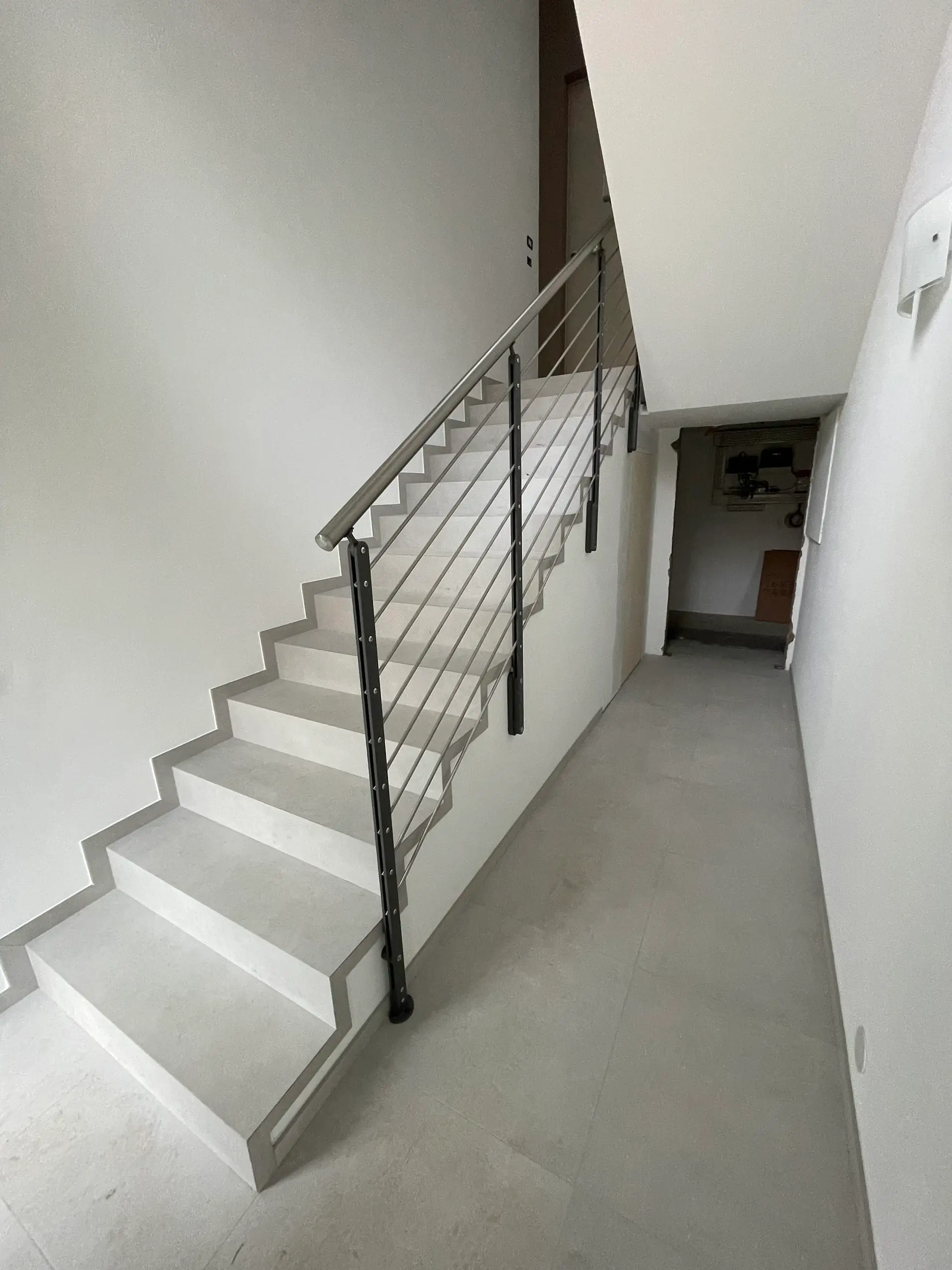 Scale interne dopo ristrutturazione Casa C.S.: gradini in resina bianca con ringhiera in acciaio nero, pareti tinteggiate e accesso soppalco moderno.